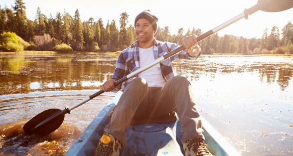Young Man Rowing Kayak On Lake